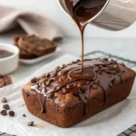 Pouring glossy chocolate ganache over a tray of banana bread squares
